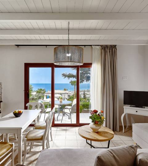 Marni Hotel Superior House Suite living and dining area with cornered sofa, dining table, TV and access to terrace