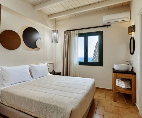 Marni Hotel Superior Suite bedroom with double bed, wooden vanity with mirror and sink, and window with sea view