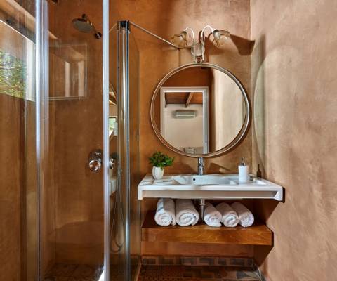 Marni Hotel Villa bathroom with round mirror, walk-in shower and rolled white towels