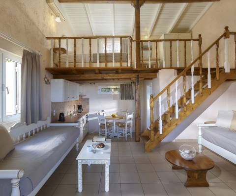 Marni Hotel Maisonette living area with two sofas, coffee tables, wooden staircase, dining table and kitchenette