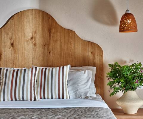 Marni Hotel Premium Studio bed with striped pillows, wooden headboard and ceramic lamp