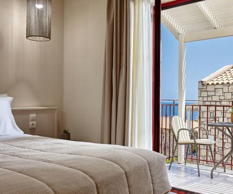 Marni Hotel Junior Suite bedroom with private balcony with sitting table and sea view
