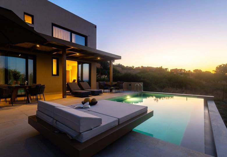 Marni Hotel Luxury Two Bedroom Villa outdoor area with private pool, wooden pergola, sitting table, an sunbeds at dusk