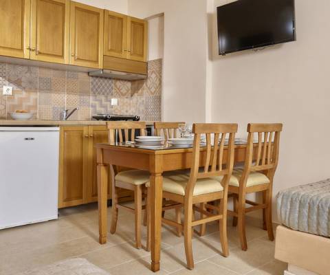 Marni Hotel Junior Apartment dining area with wooden furnishing, TV, and kitchenette