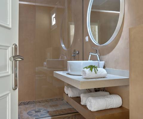Marni Hotel Studio Private Pool bathroom with round mirror, vessel sink and wooden vanity and walk in shower
