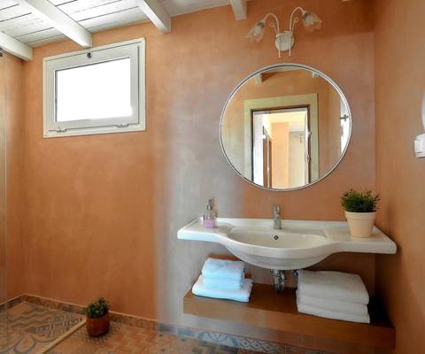 Marni Hotel Family suite bathroom with big round mirror, sink, wooden vanity and walk in shower