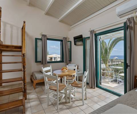 Marni Hotel Maisonette living room with dining area, sea view balcony and wooden staircase