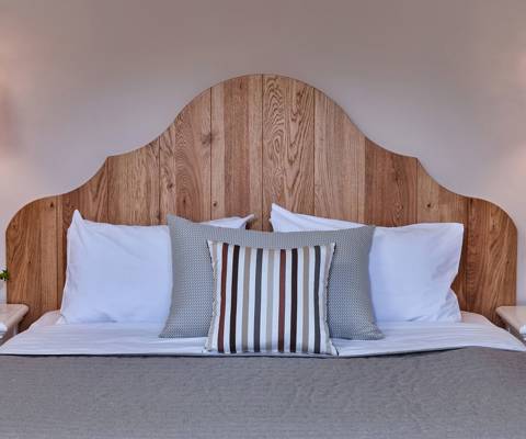 Marni Hotel Two Bedroom Apartment bed with striped pillows, wooden headboard and ceramic lamps