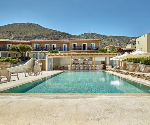Marni Village wide view of the pool bar under the wooden pergola and the shared pool with umbrellas and sunbeds