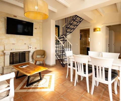 Marni Hotel Villa living room with fireplace, TV, sofa bed, dining table and modern staircase