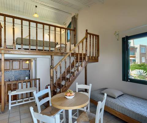 Marni Hotel Maisonette living area with dining table, wooden staircase, kitchenette and garden view
