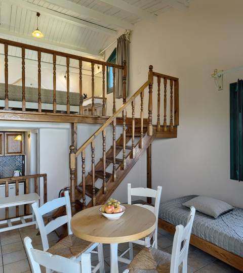 Marni Hotel Maisonette living area with dining table, wooden staircase, kitchenette and garden view