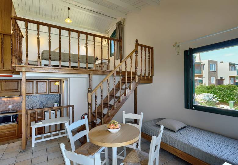 Marni Hotel Maisonette living area with dining table, wooden staircase, kitchenette and garden view