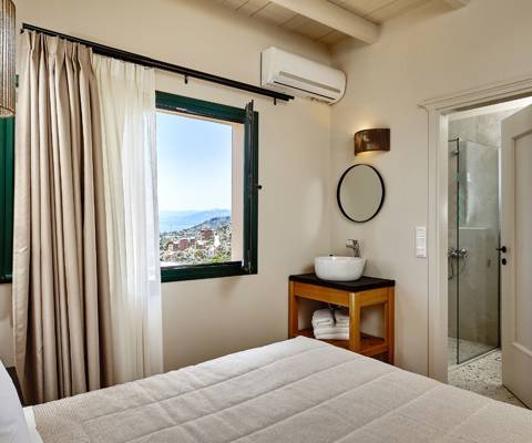 Marni Hotel Superior Suite bedroom with wooden vanity with sink, window with sea view, and bathroom access 