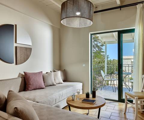 Marni Hotel Superior Suite living area with cornered sofa, coffee table and private balcony with sitting table