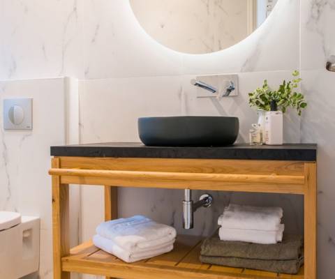Marni Hotel Studio Private Pool bathroom with round backlit mirror, black vessel sink and wooden vanity