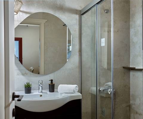 Marni Hotel Superior House Suite bathroom with round backlit mirror, sink and walk in shower