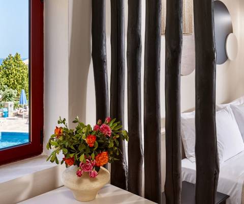 Marni Hotel Junior Suite bedroom with decorative wooden divider and window view of the pool