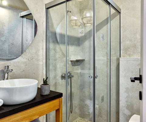 Marni Hotel Villa bathroom with round mirror, sink and walk in shower