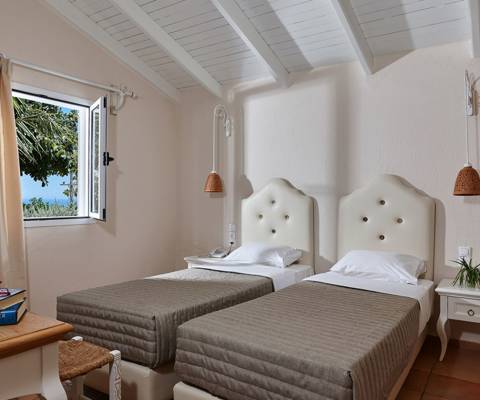 Marni Hotel Two Bedroom Apartment with twin beds, rustic decor, and window with garden and sea view