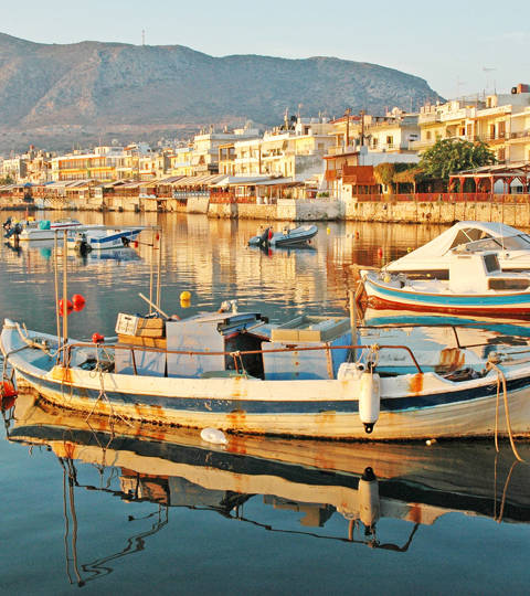 Fishing boats floating in Hersonissos harbor at sunrise