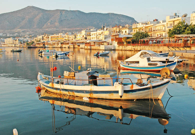 Fishing boats floating in Hersonissos harbor at sunrise