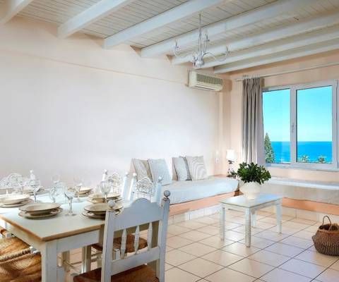 Marni Hotel Family Suite living and dining area with dining table, sofa and sea view window