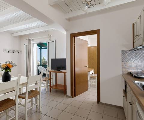 Marni Hotel Two Bedroom Apartment living area with dining table, kitchenette, TV and private balcony