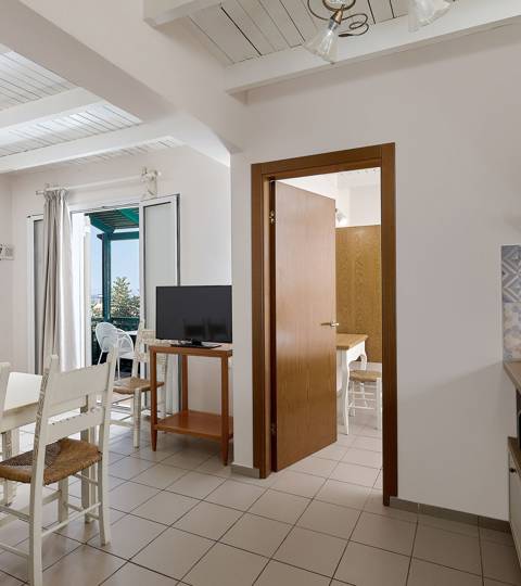 Marni Hotel Two Bedroom Apartment living area with dining table, kitchenette, TV and private balcony