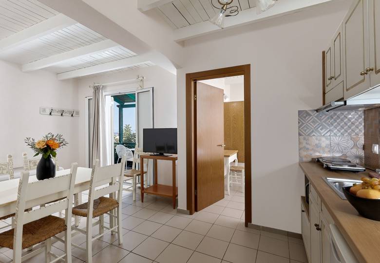 Marni Hotel Two Bedroom Apartment living area with dining table, kitchenette, TV and private balcony