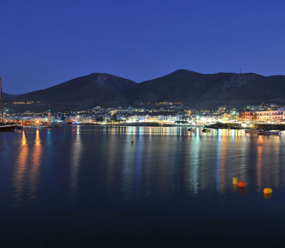 Hersonissos port by night with colorful reflections on calm sea water