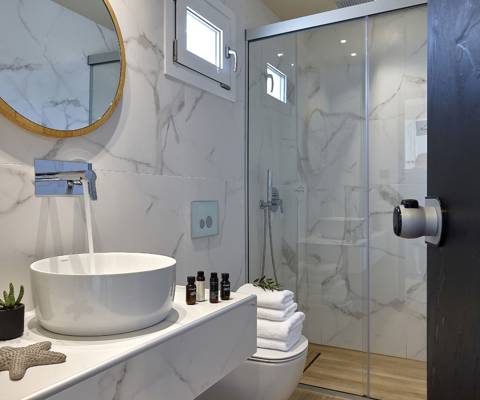 Marni Hotel Deluxe Maisonette Private Pool bathroom with round mirror, vessel sink, wooden vanity and walk in shower