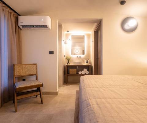 Marni Hotel Luxury Two Bedroom Villa bedroom with warm lighting, wooden chair and modern bathroom