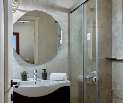 Marni Hotel Villa bathroom with round backlit mirror, sink and walk in shower bathroom with round backlit mirror, sink and walk in shower