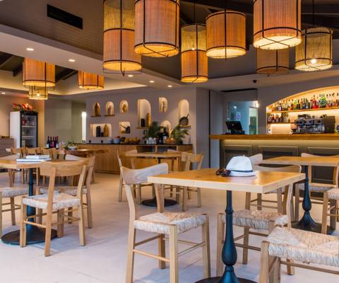 Marni Village dining area with wooden furniture, warm lighting and a fully stocked backlit bar