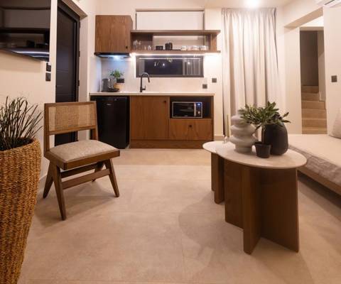 Marni Hotel Luxury Two Bedroom Villa living area with sofa, wall-mounted TV and kitchenette with modern wooden cabinets