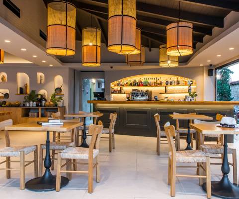 Marni Village dining area with wooden furniture, warm lighting and a fully stocked backlit bar