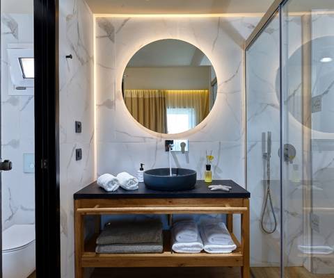Marni Hotel Bungalow Private Pool bathroom with round backlit mirror, black vessel sink and wooden vanity